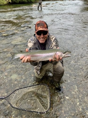 A happy angler shows off his bounty while smiling during the Alaskan fishing season.