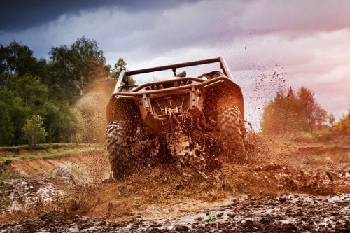 A can-am 4x4 ATV hurls mud as it takes off into the Alaskan wilderness.