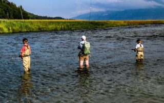 A man fishing in Alaska with kids.